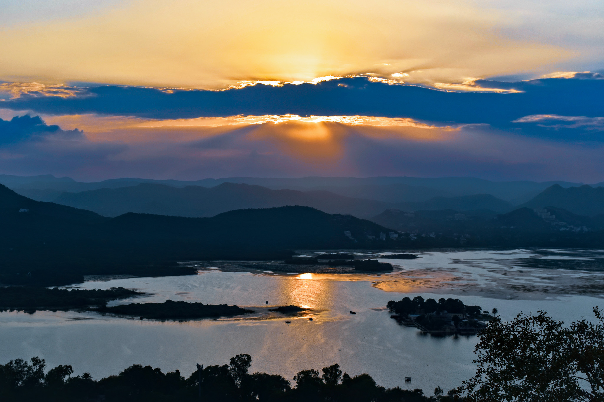 Udaipur lake sunset with glowing lights reflected across the water.